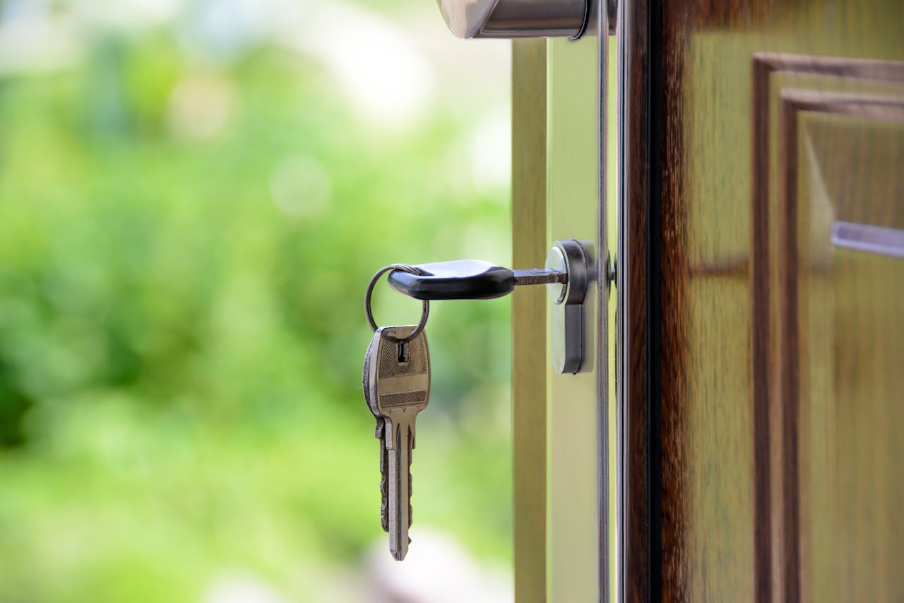 portfolio-03 Key inserted in door lock against a blurred green background, symbolizing security and real estate.