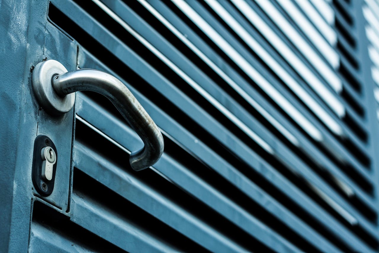 portfolio-06 Close-up of a sleek stainless steel door handle and lock on a blue metallic door.